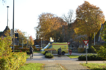 een ziekenauto met zwaailicht en sirene passeert een kruispunt