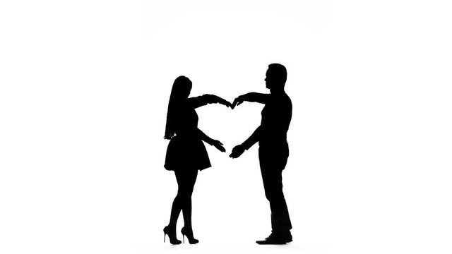Loving couple makes a heart shape with the help of hands. Silhouette. White background with