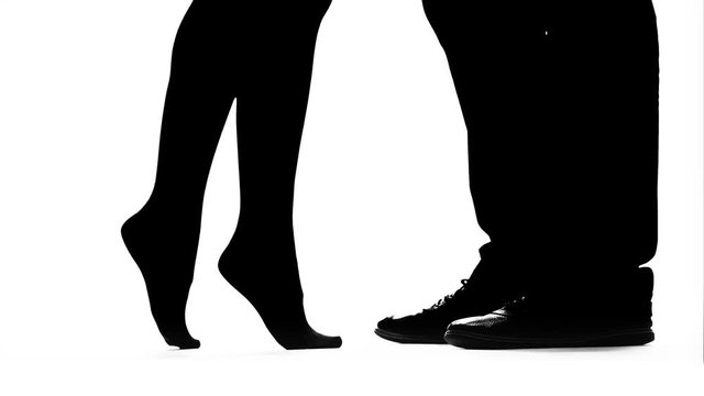 Legs of a man's girl get on toes. Silhouette. White background. Close up