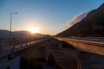 Beautiful asphalt road. Colorful landscape with high rocks, mountain road with a perfect asphalt, trees and amazing sunny cloudy sky at sunset in summer. Travel background. Highway at mountains. Road