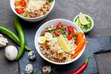 Noodles with beef meat, chili peppers and mushrooms in bowl on dark stone background.  