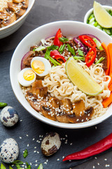 Noodles with beef meat, chili peppers and mushrooms in bowl on dark stone background.  