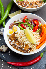 Noodles with beef meat, chili peppers and mushrooms in bowl on dark stone background. Asian Cuisine Pasta. Top view. 