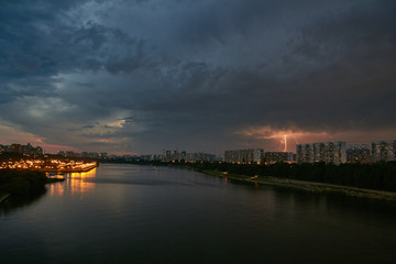 Naklejka premium Cityscape at dusk with thunderstorm over apartments buildings