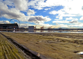 Fototapeta premium Landscape view of the waterfront in Seattle, Washington, USA from a wooden pier after rain with a wide pudle in which the clouds are reflected. 