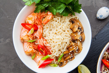 Noodles with shrimp, chili peppers and mushrooms in bowl on dark stone background. Asian Cuisine Pasta. Top view. 