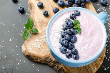 Blueberry yogurt with grated coconut on a dark stone table, close-up, selective focus