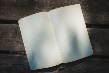 Blank empty moleskine notepad see from top on wooden table in a park