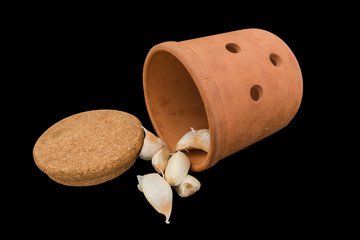 Ceramic jar inverted with cork stoppe and garlic on black background