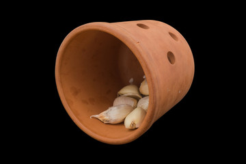 Ceramic jar inverted with garlic on black background