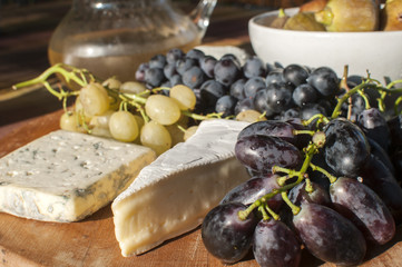 Wooden plateau with fresh grapes figs and types of cheese closeup as homefood background