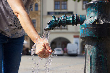 woman washing her hands in a public water pump in the city 