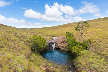 Fototapeta na wymiar Natural blue pond with small waterfall in Gran Sabana region, in south-eastern Venezuela