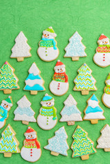 Christmas snowman and tree cookies on green background.