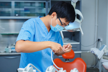 Dentist at work. Close up of young Asian doctor in medical mask working at dental clinic. Dentistry, medicine, medical equipment and stomatology concept.