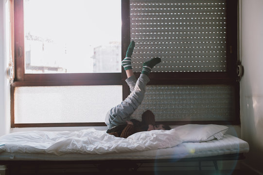 boy by the window with legs in the air
