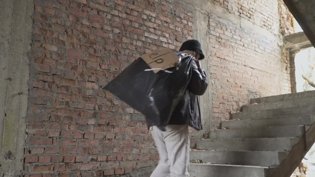 Homeless up stairs with garbage bag behind his back