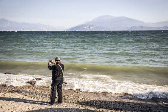 man takes a picture with the smartphone to the panorama on the lake