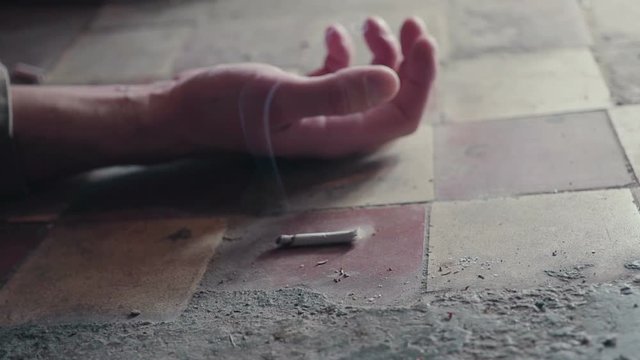 The hand of a person with a smoking cigarette. dying because of smoking . Oncological concept.