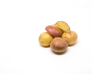 Small raw potatoes isolated on white with some potato wedges.