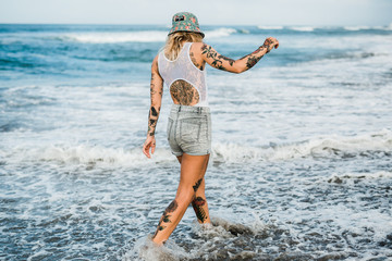 Tattooed woman walking at beach