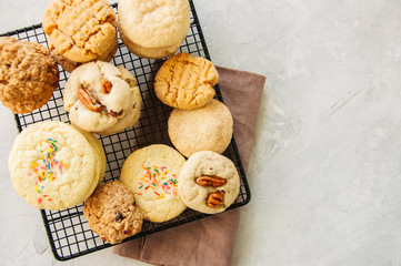 Set of festive cookies on a wire rack. Peanut butter, pecan, oatmeal, shortbread, snickerdoodle round biscuits. Top view. White stone background with copy space.