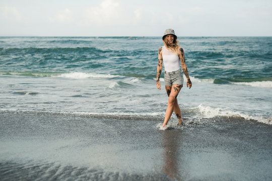 Tattooed woman walking at beach