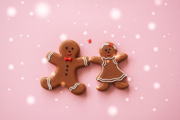 Festive Christmas concept background. Gingerbread man and girl on a pink backdrop. Toned. Top view.