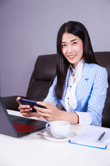 business woman sitting at the desk with laptop and using mobile phone