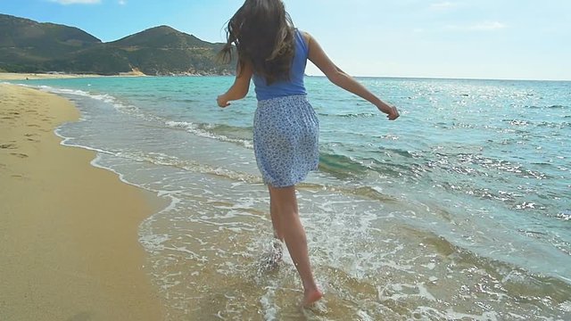 Attractive Female Running along sandy Beach. Clear blue water Slow Motion