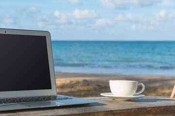 Laptop and a cup of coffee sea view