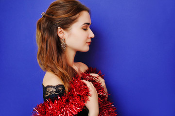 Portrait of a girl in evening black velvet dress and red shiny tinsel. New Year 2018 is coming soon.