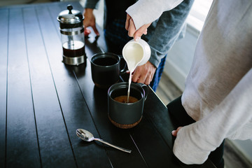 couple pouring cream in coffee