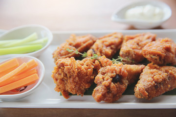 Buffalo wings barbecue chicken with carrots  and cucumbers on wood background