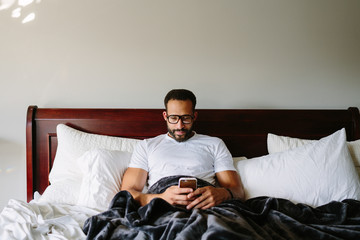 Black man working from bed on his phone