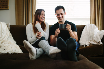 Couple sitting on the couch cuddling and drinking hot chocolate