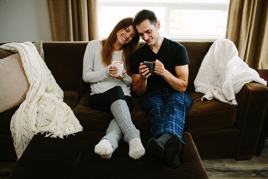 Couple Sitting On The Couch Cuddling And Drinking Hot Chocolate