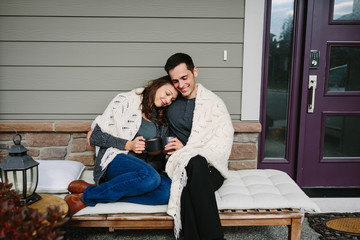 Couple in love sitting on front porch drinking coffee