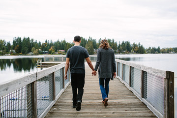 Couple holding hands walking on the pier