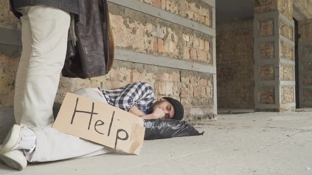 Rich man covers a sleeping homeless with jacket
