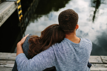 Black and white couple cuddling at the lake