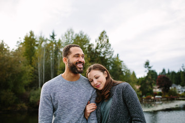 Black and white couple cuddling at the lake