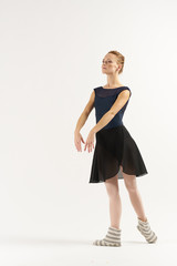 ballerina in a dark dress crosses her arms from the front