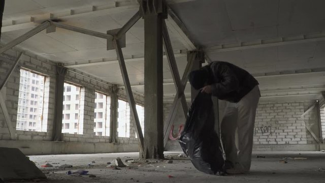 Homeless searches something in garbage bag and throws out the trash from it