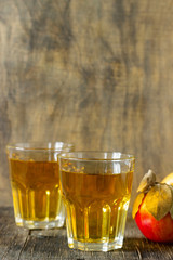Apple juice in glasses and fresh apples on a wooden background. Rustic style.