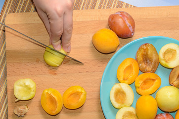 Hand cuts fruit on a wooden board