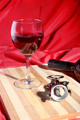 Bottle and Glass with red wine grapes and chees on wooden table.