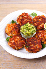 Salmon patties or cakes, lime and avocado on white plate. Fritters of fish. Salmon burgers. Healthy snack or take-away lunch bites