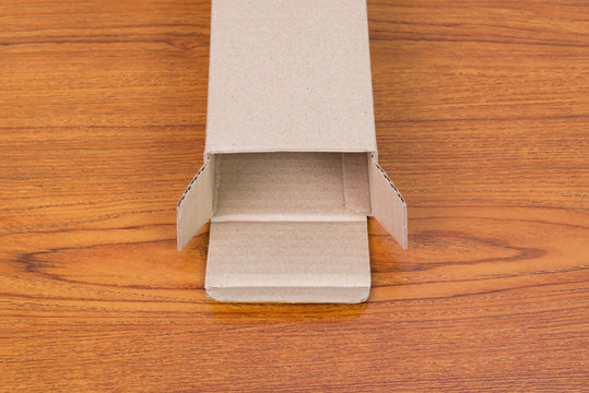 Empty opened brown cardboard box or tray for mock up on the wooden table with copy space.