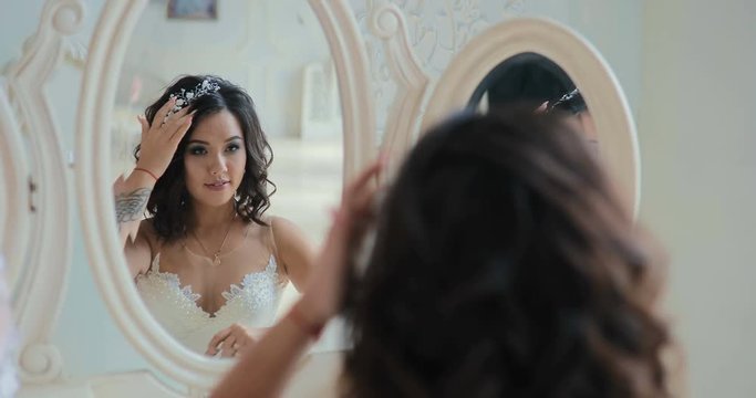 bride sits in front of the mirror / looks at the reflection